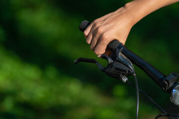 Woman's hand clutching the handle of a bicycle in the bright sunlight on a summer day close-up with copy space