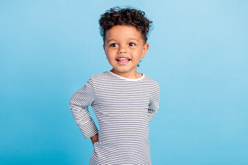Portrait of attractive cheerful wavy-haired brunette boy wearing striped shirt isolated over bright...