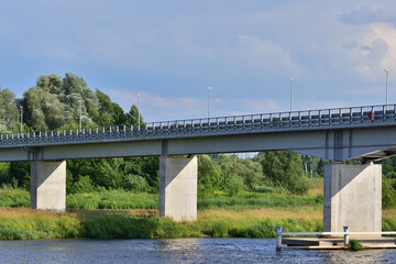 Bridge over the river between trees on a sunny day. Summer. Day.