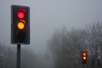 Traffic lights in fog and mist, hazardous and dangerous driving conditions.