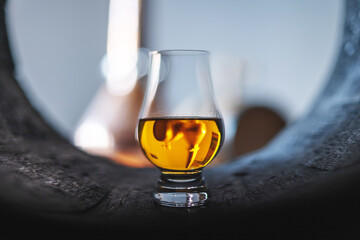 A glass of whiskey in oak barrel