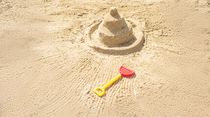 Fototapeta na wymiar Sandcastle on the blue sea in summertime and toy shovel