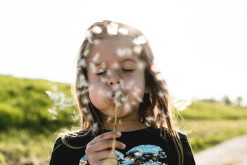 Cute little girl with dandelion flower in countryside during a spring sunny day - Female kid having...