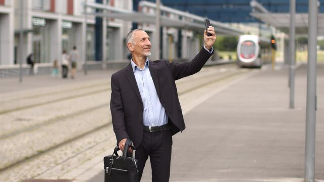 Buisnessman at train station taking selfie with smartphone
