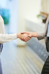 Close-up image of businesswomen shaking hands in office corridor before meeting