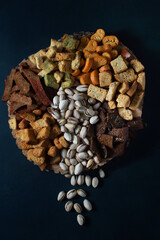 Layout of beer snacks from rusks, different tastes and pistachios. On wood, dark background, vertical orientation, top view.