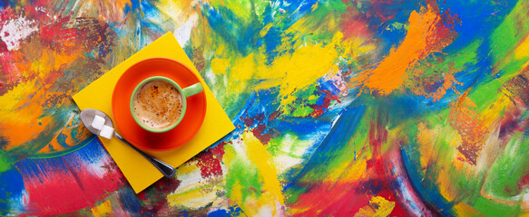 Cup of coffee and spoon with sugar at colorful abstract background texture. Coffee break