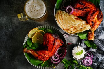 Homemade Tandoori chicken leg pieces served in a plate with roti Paratha and rice - Indian meal concept - obrazy, fototapety, plakaty