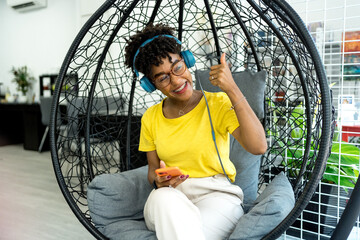 successful African American businesswoman in a modern coworking place. Front view of smiling African American freelancer with headphones using  mobile phone