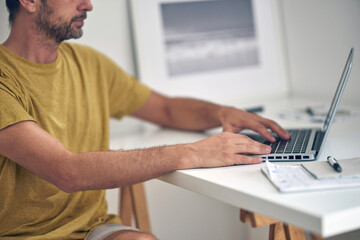Naklejka na ściany i meble Adult caucasian man working on a laptop at home.