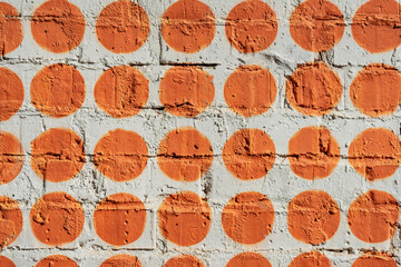 Painted many orange circles on brick wall as graffiti. Graphic abstract modern background