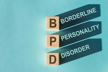 Wooden cubes building word BPD - Borderline Personality Disorder, on light blue background.