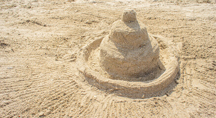 Fototapeta na wymiar Holiday concept with sandcastle on sandy beach against a summer sky and blue sea
