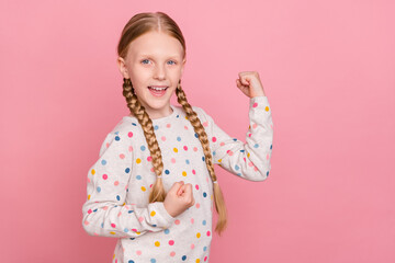 Photo of funny lucky schoolgirl dressed dotted sweater smiling rising fists isolated pink color background