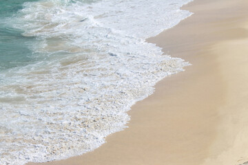White water from waves on a sandy beach on a summer day