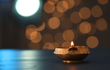 Lit diya lamp on dark table, space for text. Diwali celebration