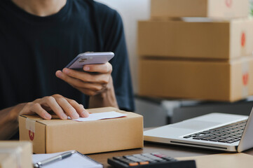 Young man entrepreneur small business SME Freelance receive order client and working with packaging sort box delivery online market on purchase order and preparing package product parcel for shipment