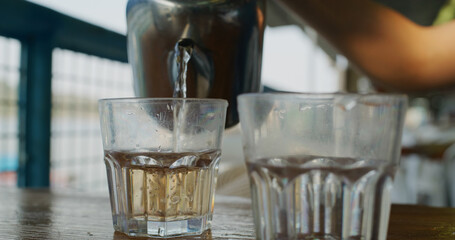 Fototapeta na wymiar Pouring tea into glass at outdoor restaurant