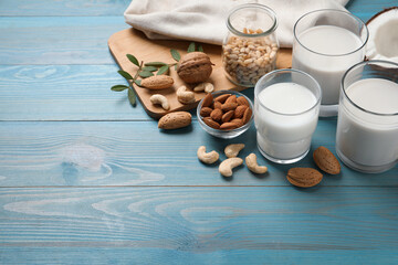 Different nut milks on light blue wooden table. Space for text