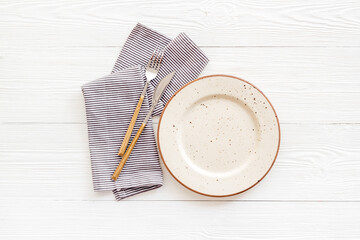 White plate with fork and knife on table napkin. Table setting