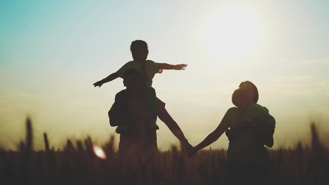 happy family in the agricultural park. silhouette of a friendly family of farmers sunset walking in a wheat field. agriculture kid dream concept silhouette. family walking in the wheat field in park