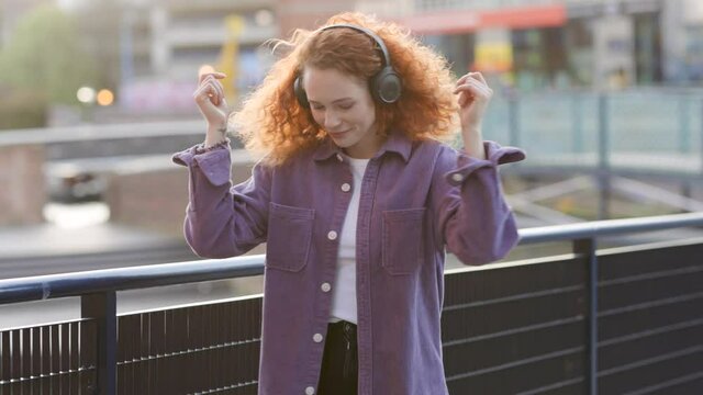 Woman dancing to music from headphones in the city