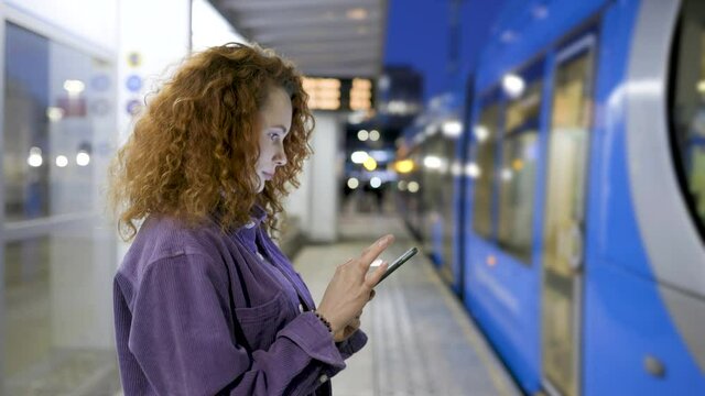 Young woman waiting for train reading text messages