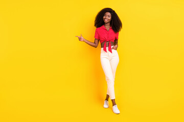 Fototapeta na wymiar Full length body size view of lovely cheerful slim girl demonstrating copy space ad offer isolated over bright yellow color background