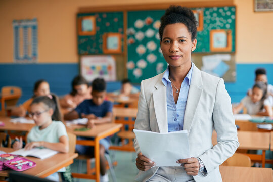 Portrait Of Black Female Elementary School Teacher In Classroom Looking At Camera.