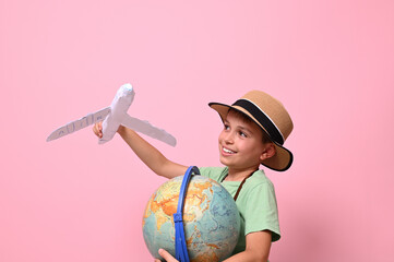 Adorable child boy plays with a paper airplane simulating a flight around the planet Earth....