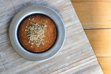 Traditional Turkish Dessert: Kunefe, Cheese and kadaif dessert with sherbet on wooden table . crumbled hazelnuts, isolated. Hatay cuisine.