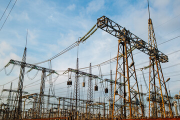 Electric pylons and high-voltage power lines against the backdrop of a bare sky with white clouds