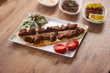 grilled meat lamb shish kebab with vegetables, mezzes and salads on wooden table. turkish barbecue. 