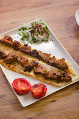 grilled meat lamb shish kebab with vegetables, mezzes and salads on wooden table. turkish barbecue. 