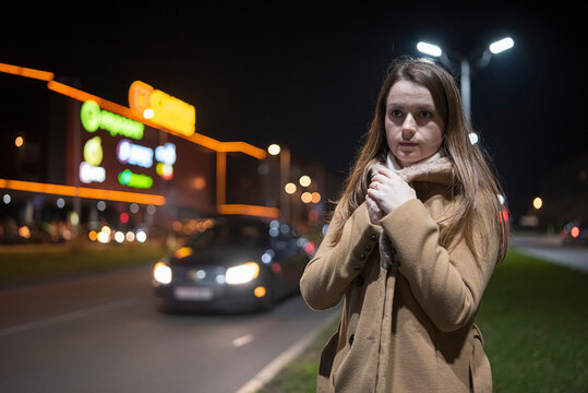 Young beautiful girl in an autumn coat on the street of the night city.