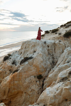 Woman standing on rocky hill on seashore