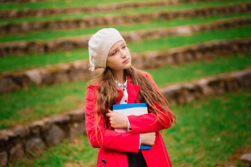 Portrait of cute schoolgirl with interesting book in natural environment