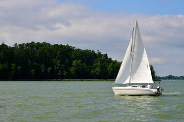 View of small boat or a passenger vessel alike with a white sail and a light body sailing slowly...