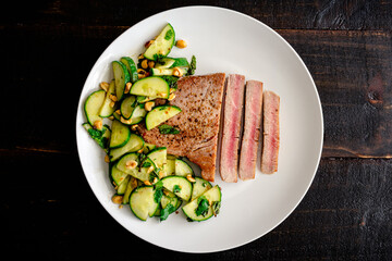 Tuna Steak with Cucumber-Peanut Salad: Rare fish fillet served with cucumber and peanut salad as a side dish