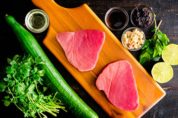 Raw Ingredients for Tuna Steaks with Cucumber-Peanut Salad: Uncooked tuna steaks, cucumber, and...