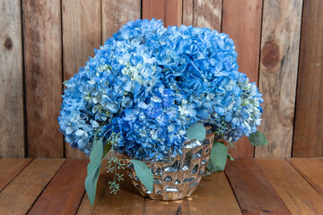 Beautiful bouquet of arranged Blue Hydrongea flowers in a silver vase given as an emotional sentiment