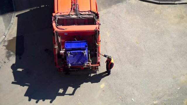 The trash can is dumped into a garbage truck. Garbage collection process.