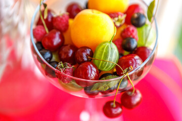 Assorted apricots, forest and garden berries in a glass glass.