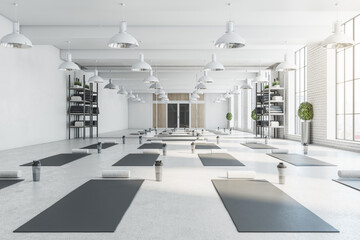 Contemporary bright white yoga studio gym interior with brick wall, window and city view. 3D...