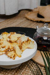 Organic dried fruits. Homemade dehydrated fruit chips on a white round tray. The concept of healthy eating. dried pineapple top view. Glass teapot with tea.