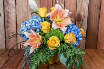 Large Stargazer flowers tops this arrangement of roses and blue hydrangea flowers and greenery