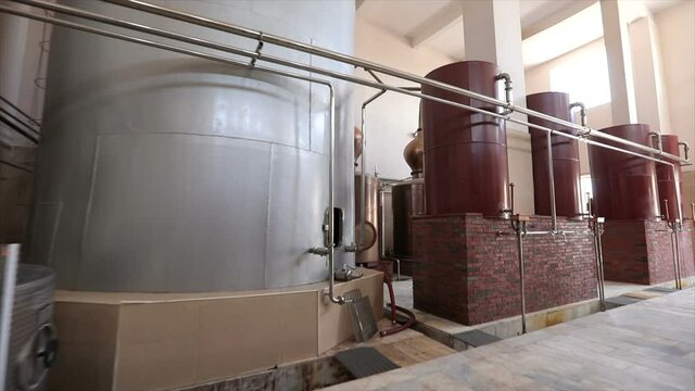Large stainless steel brandy distilling tanks. Silos for wine and cognac fermentation . Steel barrels for fermentation of wine in winemaker factory . Dolly , ronin movement a long row of spirit vats .