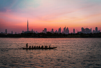 sunset image from Dubai skyline with traditional boat riders