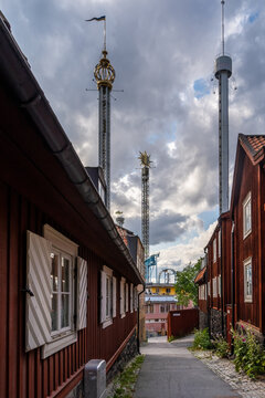 Perspective view of old vintage red wooden buildings in Stockholm with the amusement park towers of Gröna Lund in the background.