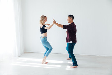 Fototapeta na wymiar a man and a woman dance bachata to music in a white room